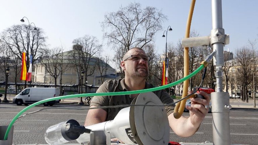Un technicien d'Airparif paramètre un appareil de mesure de la pollution dans l'air sur le toit de sa voiture, le 23 mars 2015 sur les Champs Elysées