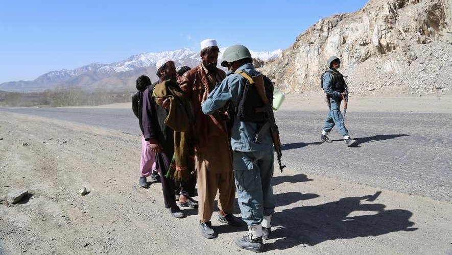Des policiers afghans contrôlent des civils sur une route de la province de Wardak, en 2013