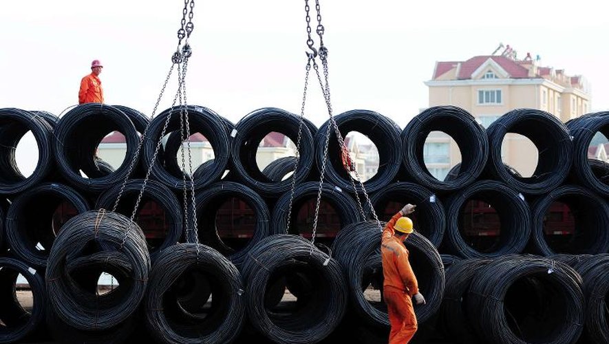 Des employés manoeuvrent des rouleaux de fil d'acier sur le port de Qingdao, dans l'est de la Chine, le 17 mai 2014