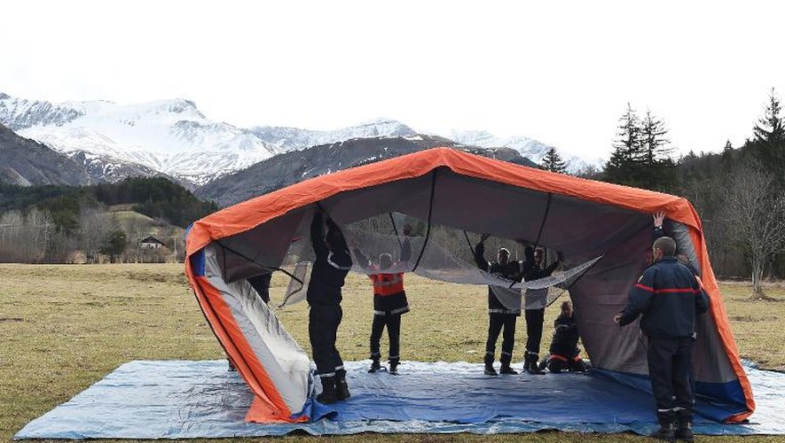Installation d'une grande tente orange dans un champ pour une cérémonie de recueillement le 25 mars 2015 au Vernet