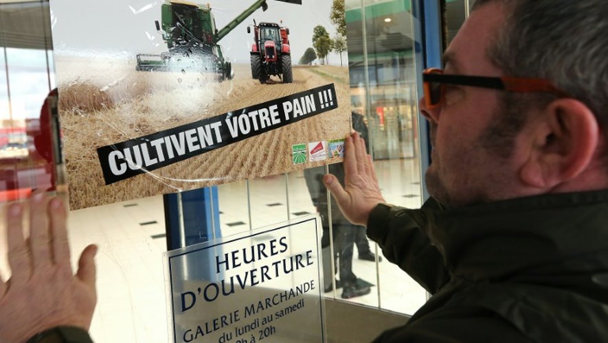 Un agriculteur pose une affiche sur un supermarché Cora pendant une manifestation à Reims, le 11 février 2016