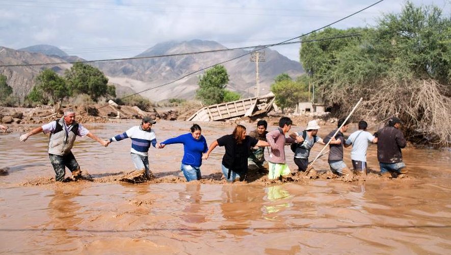 Des habitants traversent ensemble une route inondée près de Copiapo, dans le désert d'Atacama, au Chili, le 26 mars 2015