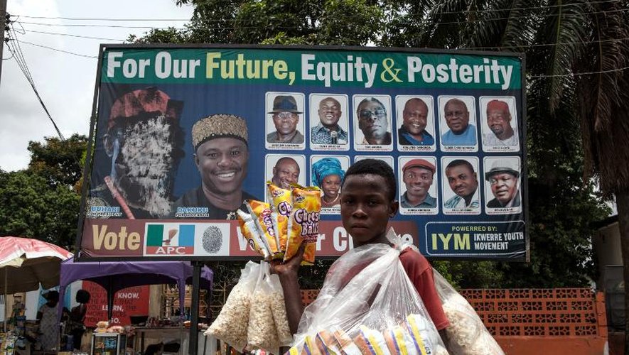 Un jeune vendeur de popcorn passe devant une affiche appelant à voter pour l'ancien général Muhammadu Buhari, le 26 mars 2015 dans la ville nigériane de Port Harcourt