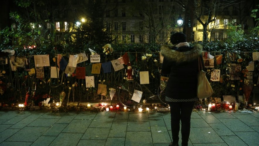 Une femme lit des message laissés près de bougies sur le trottoir en face de la salle de concert du Bataclan, à Paris, le 31 décembre 2015