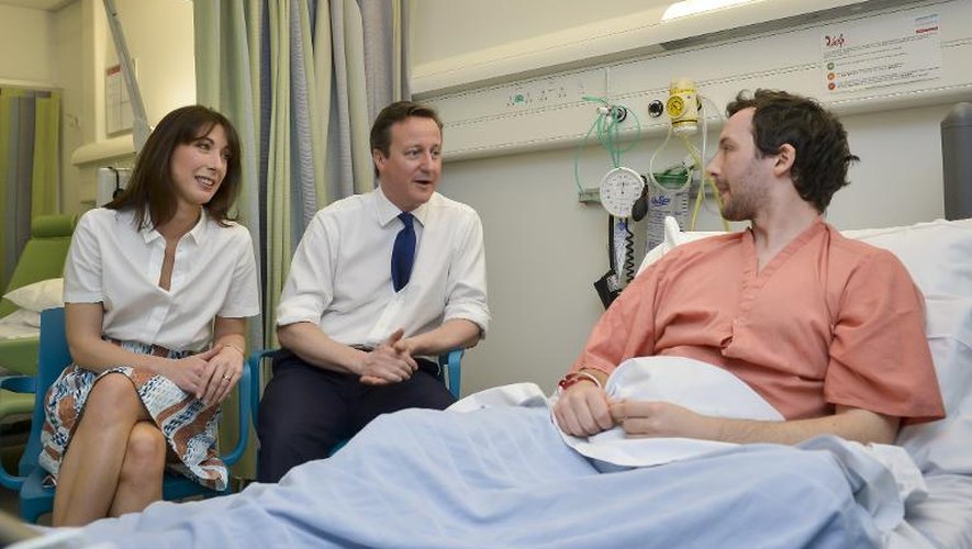 Le Premier ministre britannique David Cameron  et son épouse Samantha au côté d'un patient à l'hôpital Royal Salford à Manchester le 28 mars 2015