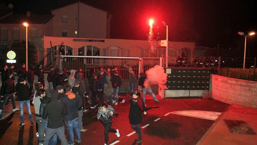 Des manifestants cagoulés ou portant des capuches lancent divers projectiles -pierres, planches, gros pétards - en direction des gendarmes mobiles venus de Bastia, le 15 février 2016 à Corte