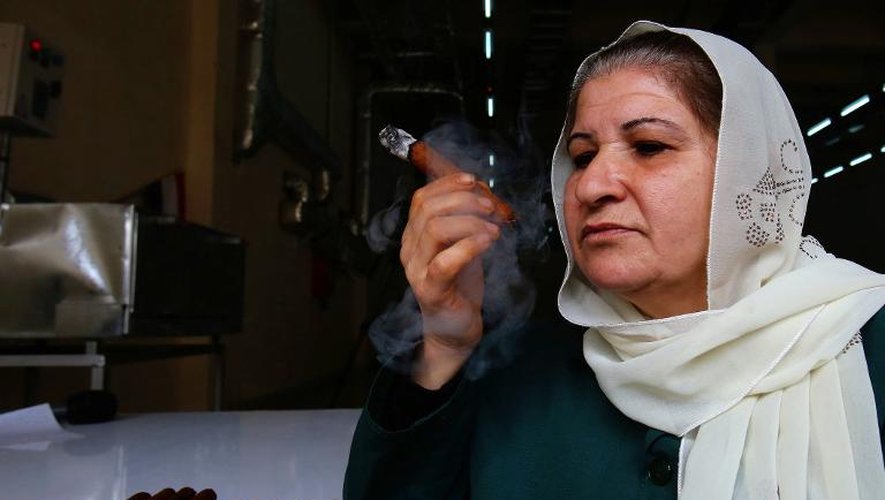 L'employée Oum Ali fume un cigare produit dans la première usine syrienne de fabrication de cigares, la Compagnie générale du tabac le 17 mars 2015
