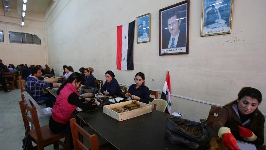 Photo prise le 17 mars de la grande salle de la Compagnie générale du tabac à Lattaquié, dont les murs sont ornés des portraits du président Bachar al-Assad et de son père défunt