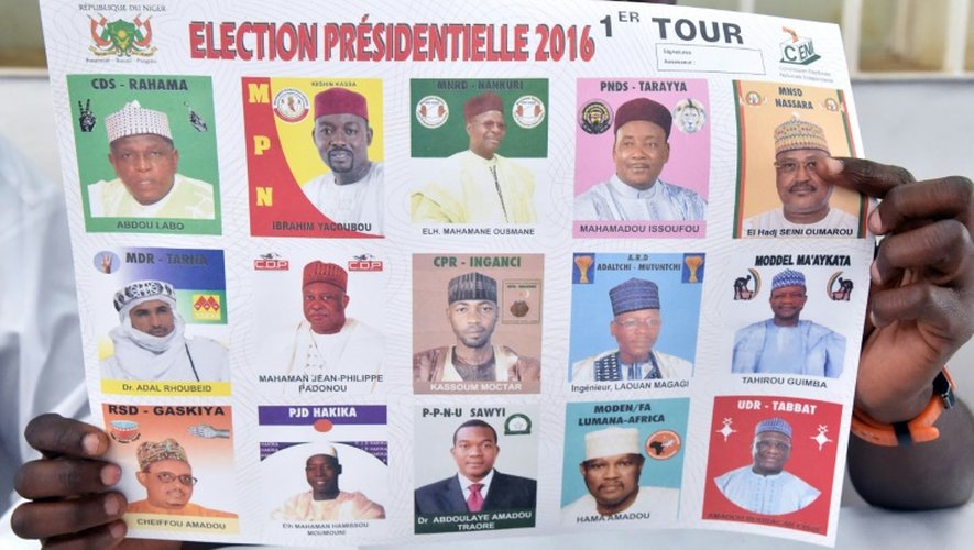 Un employé d'un bureau de vote montre les portraits des différents candidats à l'élection présidentielle au Niger, à Niamey, le 21 février 2016