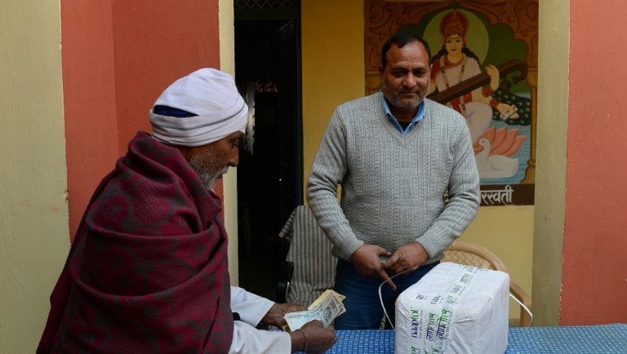 Le postier Chetram (g) livre un paquet commandé sur internet à un client dans un village du district de Neemrana dans le Rajasthan, le 21 janvier 2016