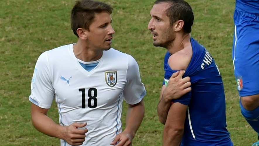 Le défenseur italien Giorgio Chiellini (d) montre la morsure à l'épaule infligée par le milieu uruguayen Luis Suarez (g) au Mondial, le 24 juin 2014 à Natal au Brésil