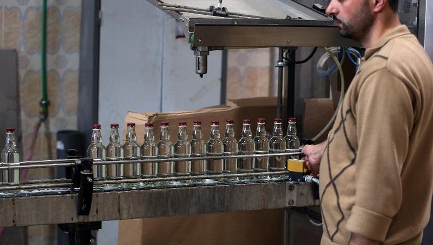 Un employé contrôle une ligne de production de bouteilles d'arak, de l'entreprise Al Minas à Homs (centre de la Syrie), le 26 mars 2015