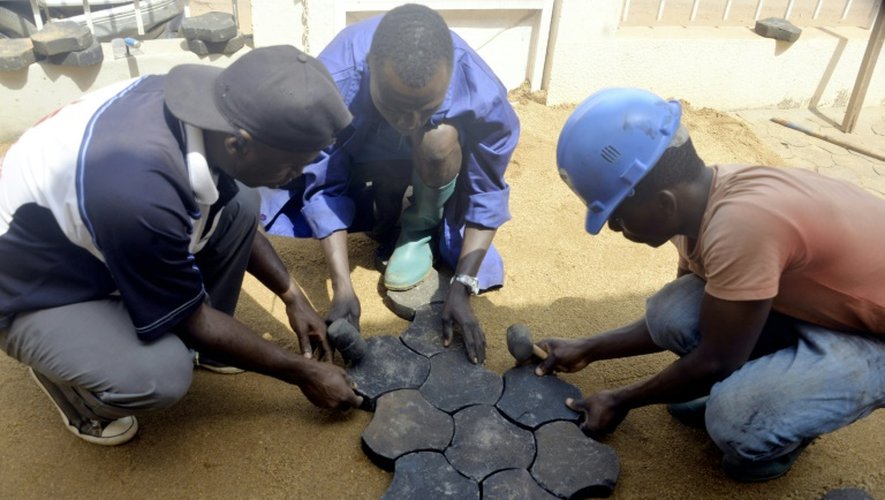 Des Camerounais pavent le sol avec des pavés fabriqués avec des déchets plastiques recyclés, le 1er février 2016 à Yaoundé