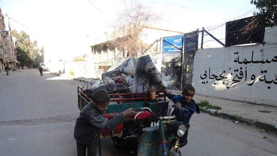 Des garçonnets poussent un véhicule dans une rue du camp de réfugiés palestiniens de Yarmouk, dans le sud de Damas, le 4 avril 2015