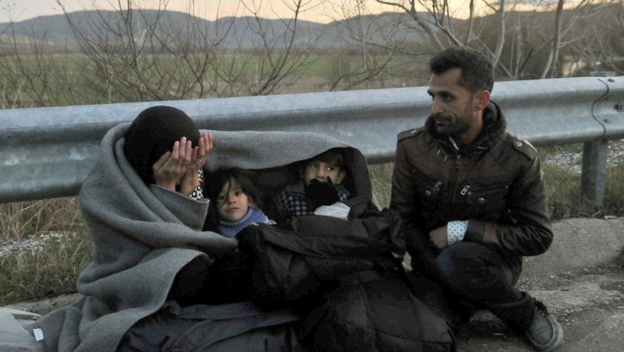 Une famille de réfugiés attend de passer la frontière entre la Grèce et la Macédoine, près du village grec d'Idomeni, dans la nuit du 21 février 2016