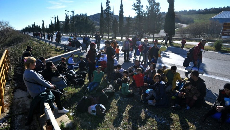 Des migrants attendent sur le bord d'une route, sur leur trajet pour traverser la frontière de la Grèce vers la Macédoine, près du village d'Idomeni le 21 février 2016