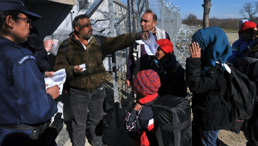 Des policiers contrôlent les passeports de migrants qui tentent de traverser la frontière de la Grèce vers la Macédoine, près du village d'Idomeni le 21 février 2016