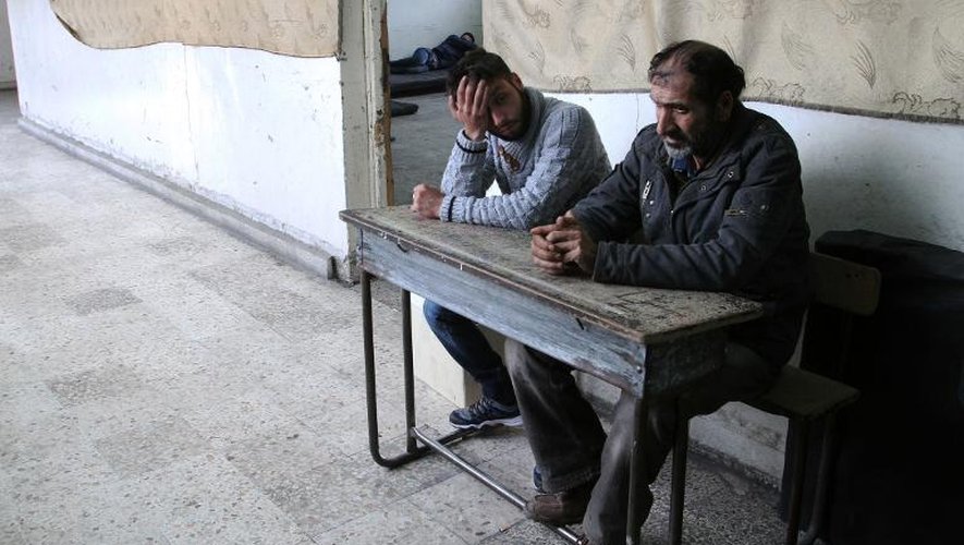 Des Palestiniens qui se sont enfuis du camp de Yarmuk sont assis sur un banc, à l'intérieur d'une école à Damas, le 6 avril 2015