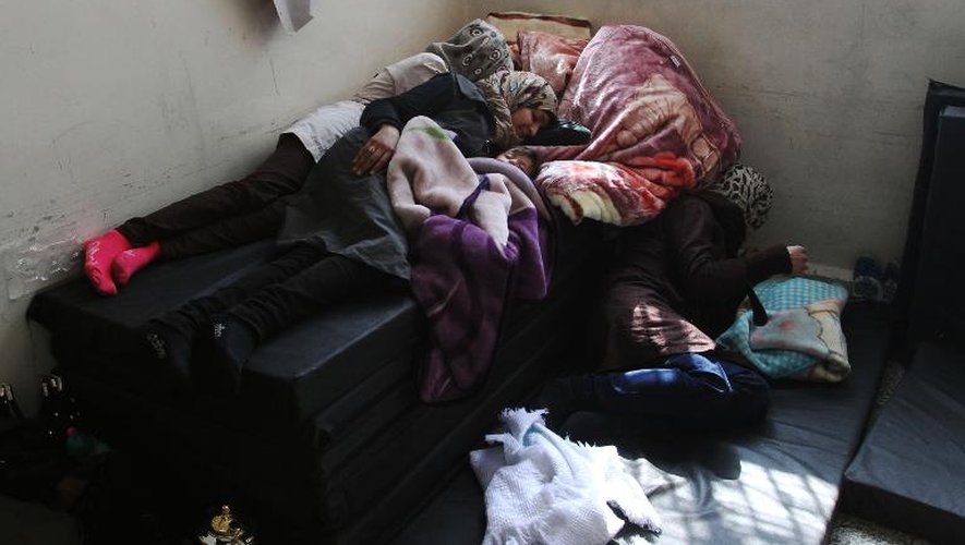 Deux femmes qui ont fui le camp de réfugiés palestinien de Yarmuk sont allongées sur un matelas dans une école à Damas, le 6 avril 2015