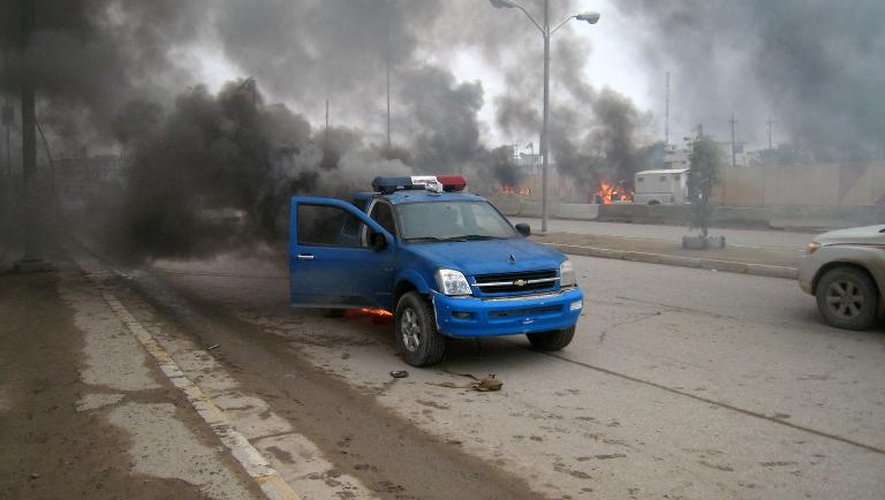 De la fumée s'échappe d'une voiture de police après des affontements entre jihadistes et forces irakiennes le 1er janvier 2014 à Fallouja, à l'ouest de Bagdad
