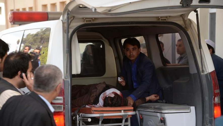 Un afghan assis dans une ambulance accompagne une victime tuée lors de l'attaque menée par des talibans contre une cour d'appel de Mazar-i-Sharif (nord), le 9 avril 2015