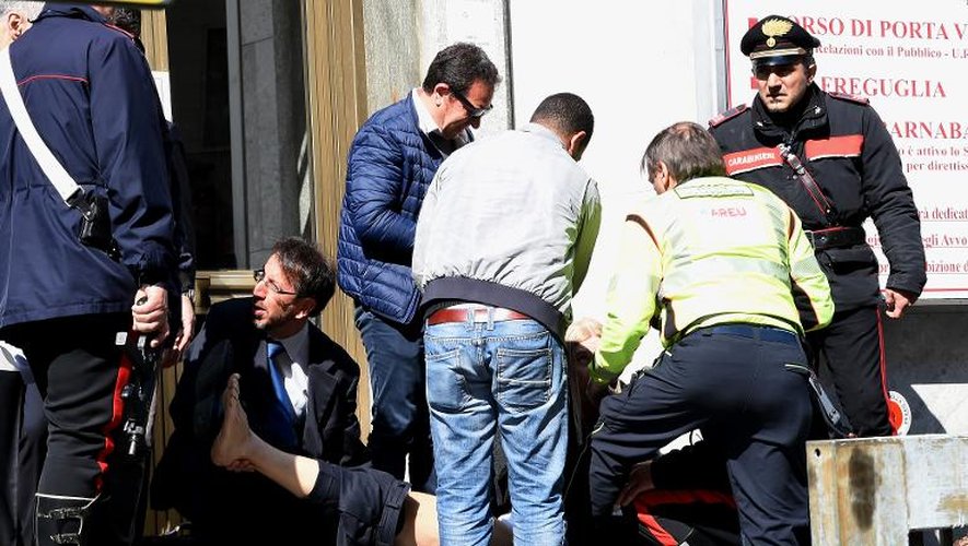 Des gens aident un blessé par un homme qui a ouvert le feu jeudi matin au tribunal de Milan, provoquant la mort de trois personnes, dont un juge