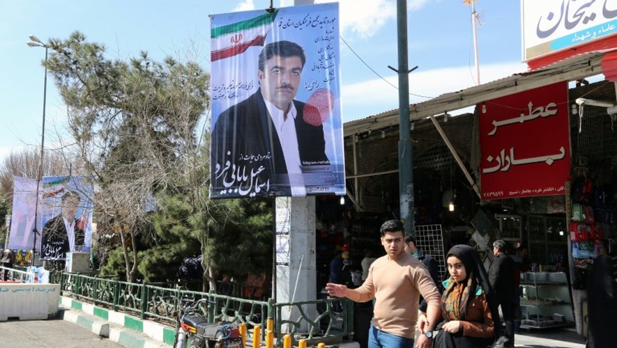 Des Iraniens passent devant un panneau électoral, le 24 février 2016 à Qom (130 km de Téhéran)