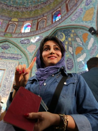 Une Iranienne montre son index marqué à l'encre après avoir déposé son bulletin dans l'urne dans un bureau de vote de Téhéran le 26 février 2016