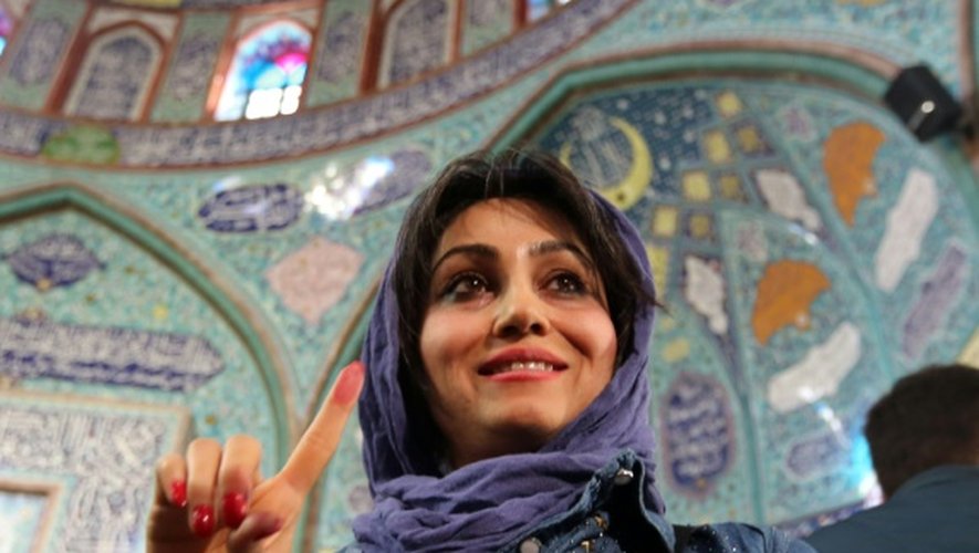 Une Iranienne montre son index marqué à l'encre après avoir déposé son bulletin dans l'urne dans un bureau de vote de Téhéran le 26 février 2016