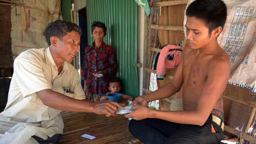Le médecin sans diplôme Ken Mon (g) donne un médicament à un de ses patients, le 27 février 2015 à Kampong Speu, au Cambodge