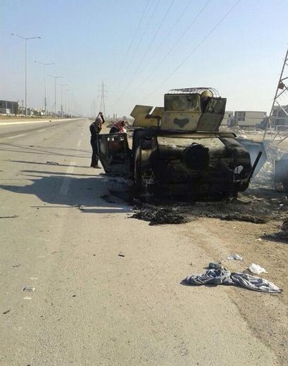 Des Irakiens inspectent les restes d'un véhicule de l'armée irakienne sur l'autoroute menant à Ramadi, la capitale de la province d'Al-Anbar, le 7 janvier 2014, après des combats la veille entre les troupes irakiennes et les jihadistes
