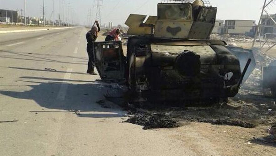 Des Irakiens inspectent les restes d'un véhicule de l'armée irakienne sur l'autoroute menant à Ramadi, la capitale de la province d'Al-Anbar, le 7 janvier 2014, après des combats la veille entre les troupes irakiennes et les jihadistes