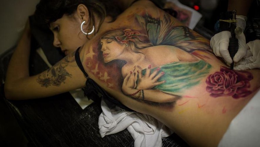 Une jeune femme brésilienne se fait tatouer le dos, le 5 janvier 2014 à Rio de Janeiro pendant la semaine du tatouage