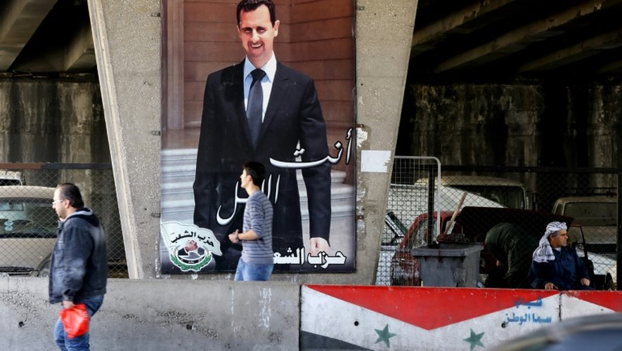 Un Syrien passe devant un portrait géant du président Assad dans une rue de Damas, le 26 février 2016