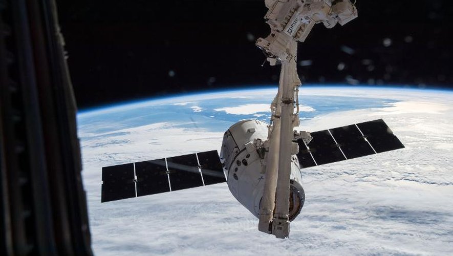 Photo fournie par la NASA et prise par l'équipage de la Station Spatiale Internationale (ISS) montrant le bras robotique de la station saisissant la capsule Dragon le 12 janvier 2015