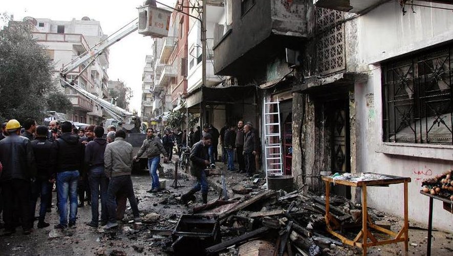 Des Syriens constatent les dégâts sur des bâtiments après une attaque au mortier à Homs, le 9 janvier 2014