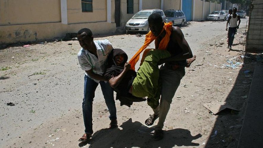 Un des blessés de l'attentat à la voiture piégée devant le ministère de l'Education somalien est transporté par deux personnes le 14 avril 2015 à Mogadiscio