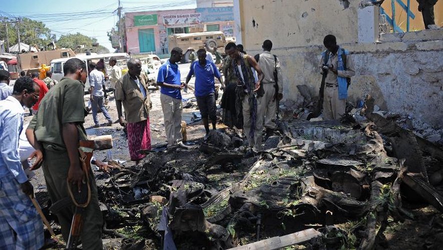 Des passants observent les restes de la voiture piégée qui a explosé le 15 avril 2015 devant le ministère de l'Education somalien à Mogadiscio