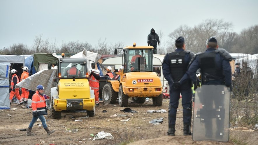 Des policiers surveillent le démantèlement d'abris dans la "jungle" de Calais par des bulldozers, le 1er mars 2016