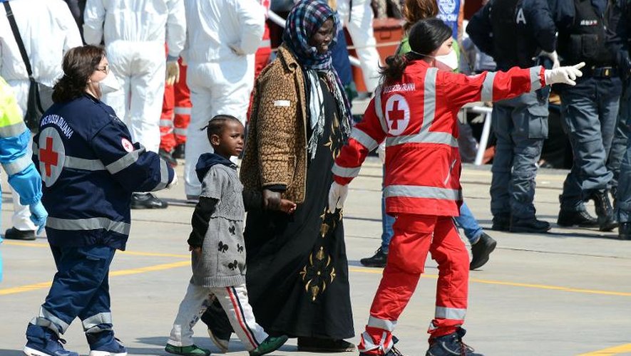 Des membres de la Croix Touge escortent des migrants qui arrivent dans le port de Messine, en Sicile, le 15 avril 2015