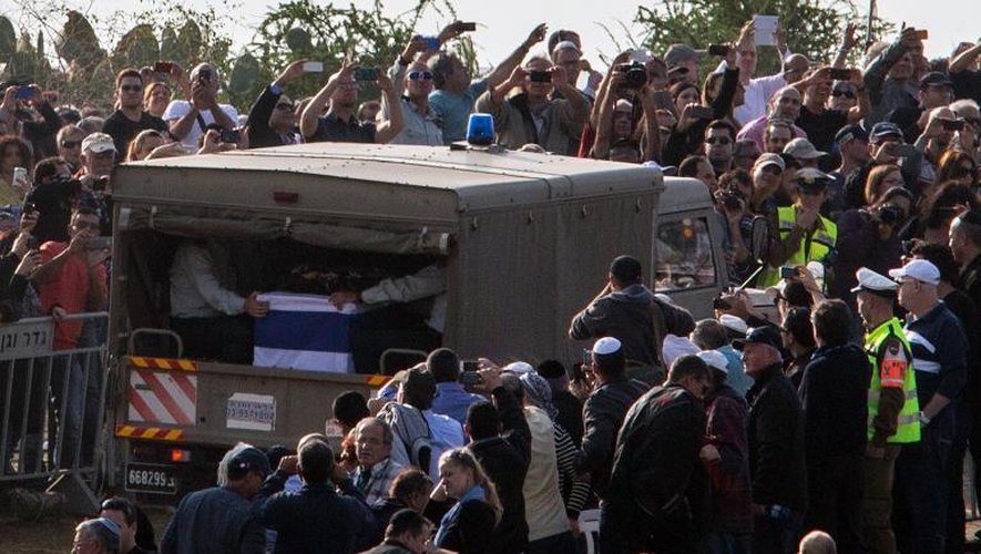 Des Israéliens prennent des photos du convoi transportant la dépouille d'Ariel Sharon à son arrivée au lieu de sa sépulture près de la ville de Sderot, le 13 janvier 2014