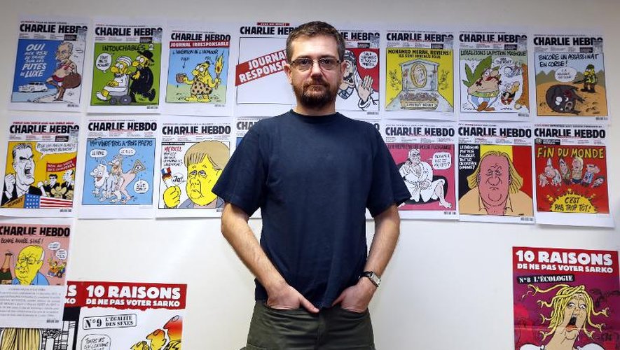 Le dessinateur Charb pose devant les Unes de Charlie Hebdo, dont il était le directeur, le 27 décembre 2012, le jour où il présentait à la presse un album intitulé "La Vie de Mahomet"