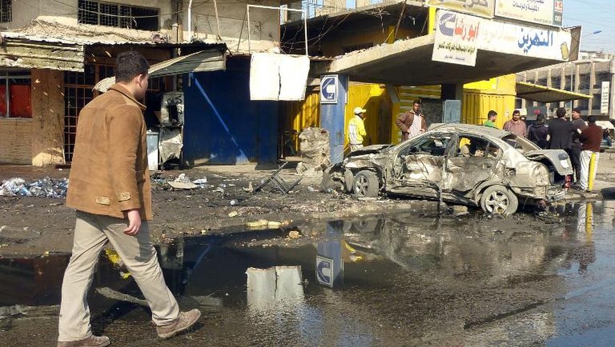 Des habitants sur les lieux d'un attentat à la voiture piégée, le 15 janvier 2014 à Bagdad