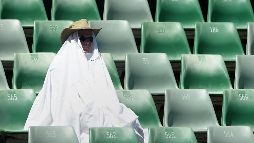 Un spectateur se protège de la chaleur le 16 janvier 2014 à Melbourne durant l'Open d'Australie de tennis