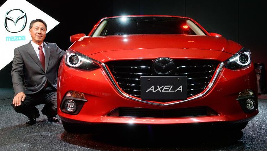 Le président du constructeur japonais Mazda, Masamichi Kogai, pose le 20 novembre 2013 aux côtés d'un nouveau modèle présenté au salon de l'automobile de Tokyo