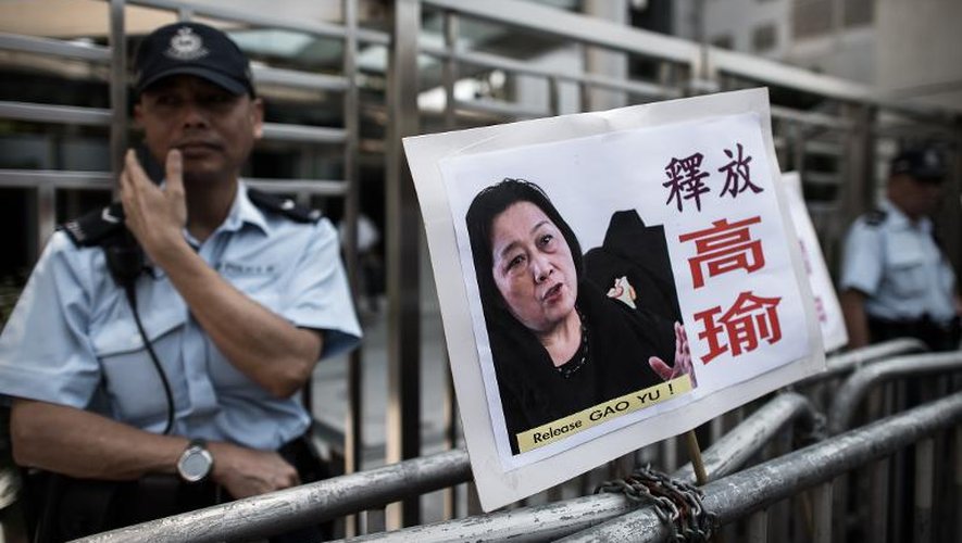 Un policier monte la garde devant le Bureau de liaison chinois à Hong Kong sur lequel a été placardé par des manifestants un portrait de la journaliste chinoise Gao Yu, le 17 avril 2015