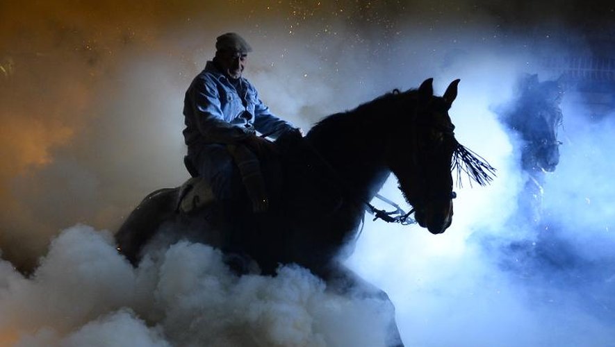 A la fête traditionnelle de San Bartolomé de Pinares, en Espagne, un cavalier et son cheval s'élancent sur des brasiers, le 16 janvier 2014