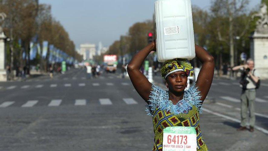 Lors du marathon de Paris, le 12 avril 2015, une Gambienne, Siabatou Sanneh, porte un bidon sur la tête pour sensibiliser l'opinion aux kilomètres parcourus en Afrique pour chercher de l'eau