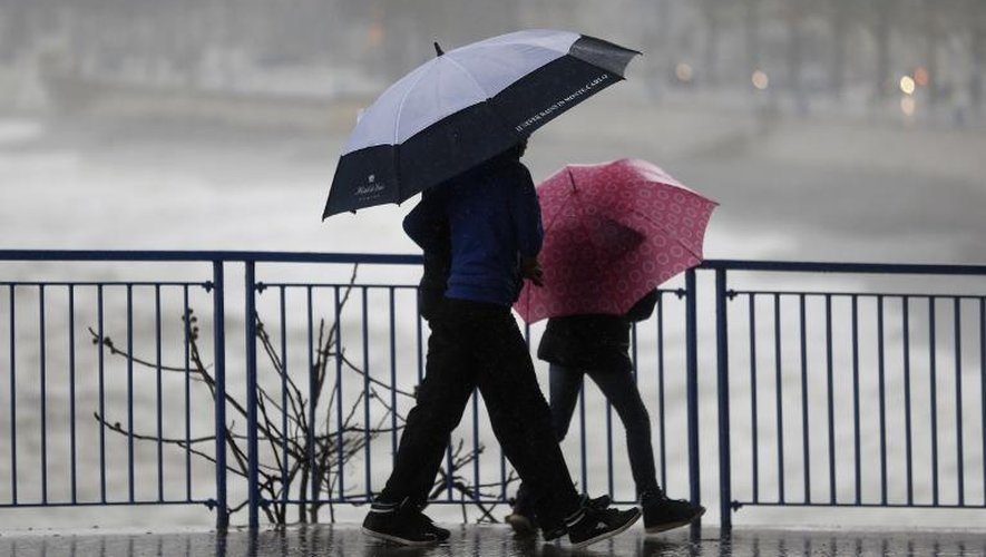 Des passants à Nice lors de fortes pluies et rafales de vent, le 25 décembre 2013