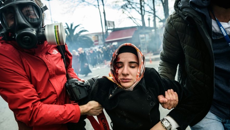 Des journalistes portent une femme blessée après des tirs de grenades lacrymogènes par la police anti-émeutes turque pour disperser une manifestation de soutien au quotidien Zaman, le 5 mars 2016 à Istanbul